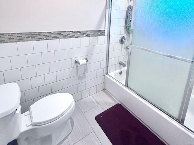 bathroom featuring shower / bath combination with glass door, tile walls, and toilet