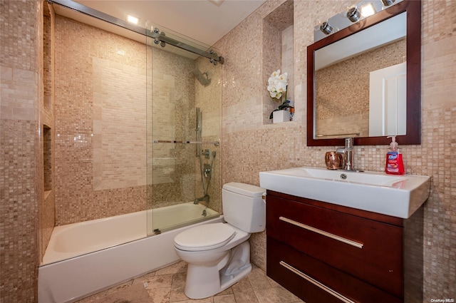 full bathroom featuring combined bath / shower with glass door, backsplash, vanity, tile walls, and toilet