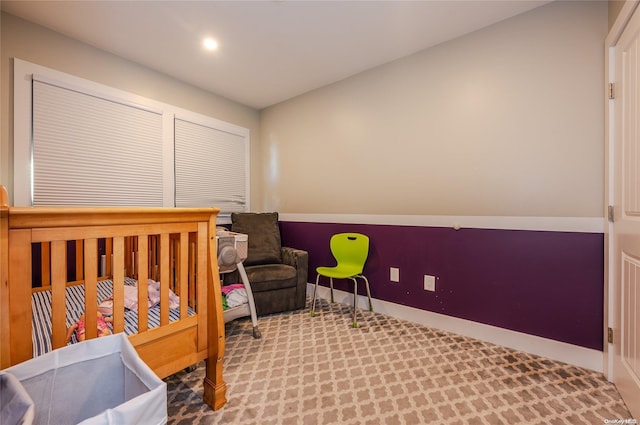 bedroom with light carpet and a nursery area