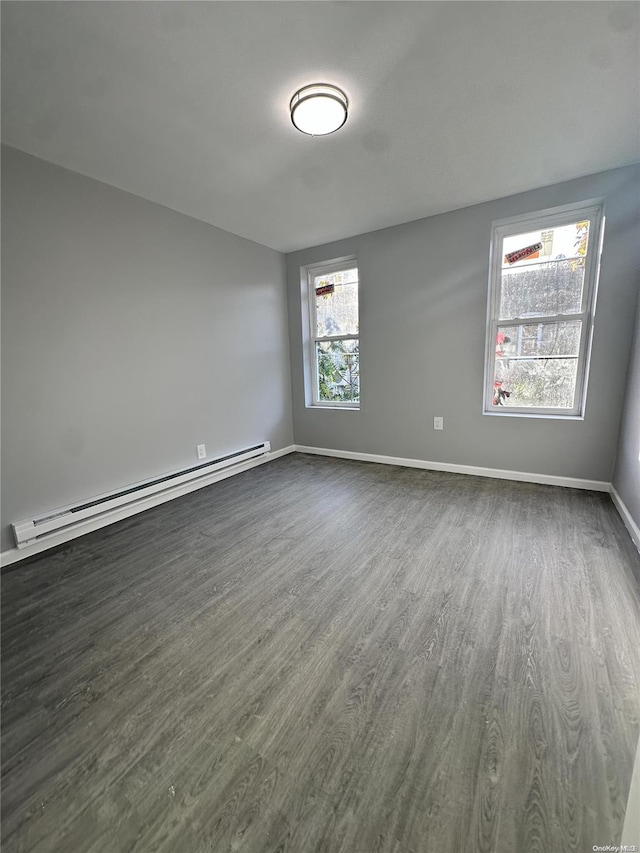 empty room with dark hardwood / wood-style flooring and a baseboard heating unit