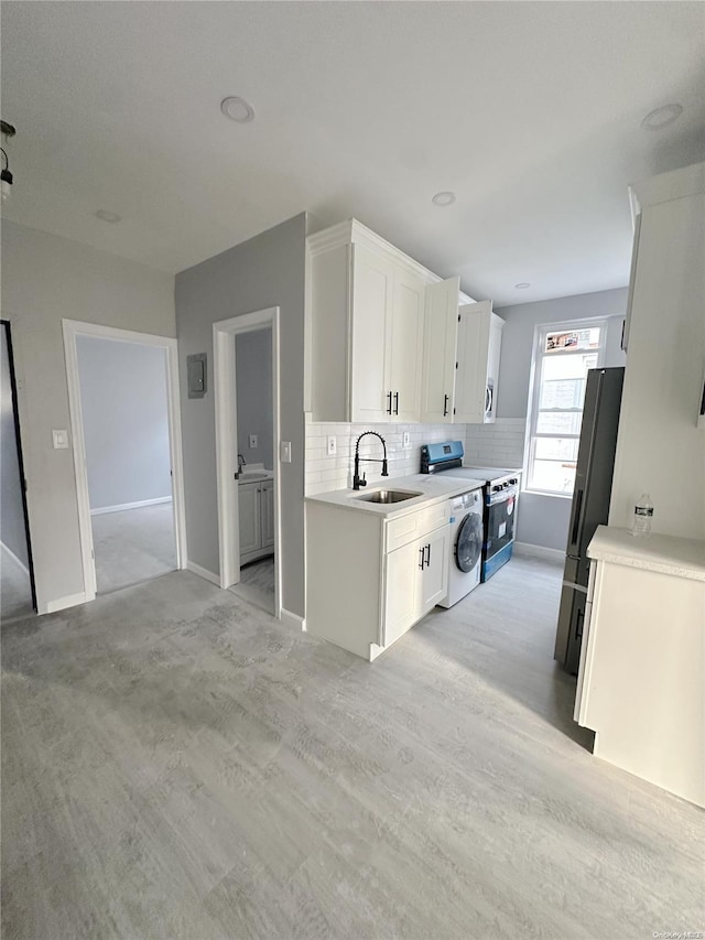 kitchen featuring tasteful backsplash, electric stove, sink, washer / clothes dryer, and white cabinetry