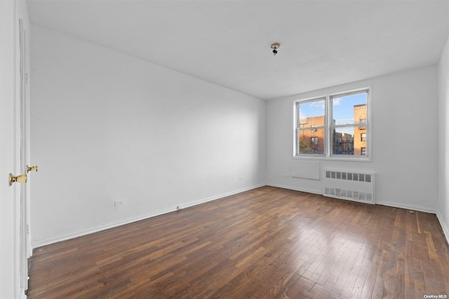 spare room with dark hardwood / wood-style flooring and radiator