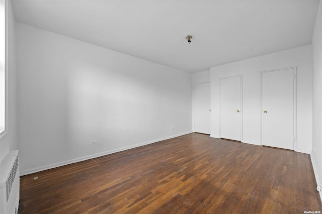 unfurnished bedroom with dark hardwood / wood-style flooring and radiator