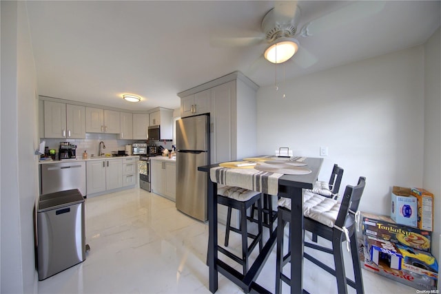 kitchen featuring decorative backsplash, sink, ceiling fan, and appliances with stainless steel finishes