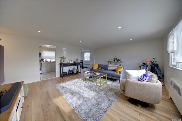 living room featuring plenty of natural light, radiator heating unit, and light hardwood / wood-style flooring