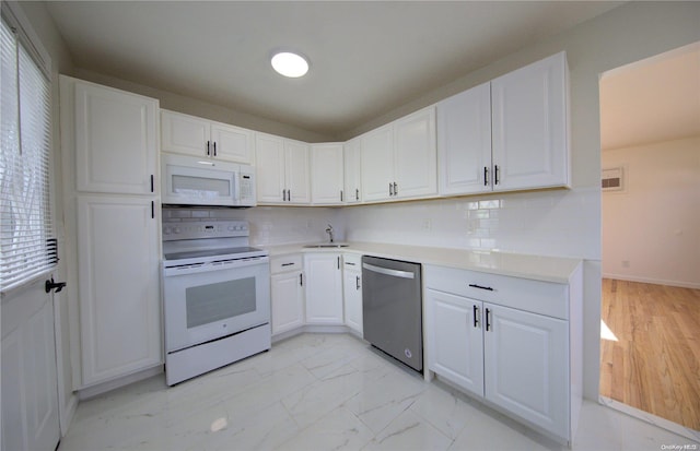 kitchen with tasteful backsplash, white cabinetry, sink, and white appliances