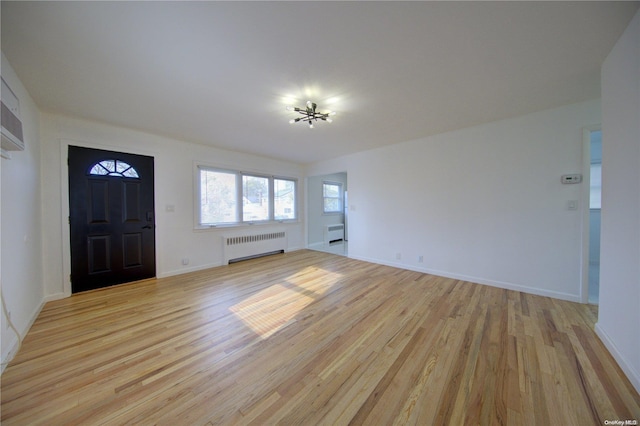 foyer entrance featuring light hardwood / wood-style floors, radiator, and a notable chandelier