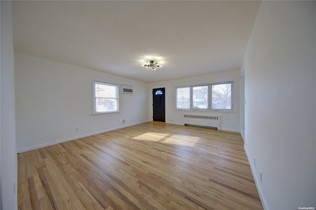 empty room featuring light hardwood / wood-style floors, radiator, and a wall mounted AC