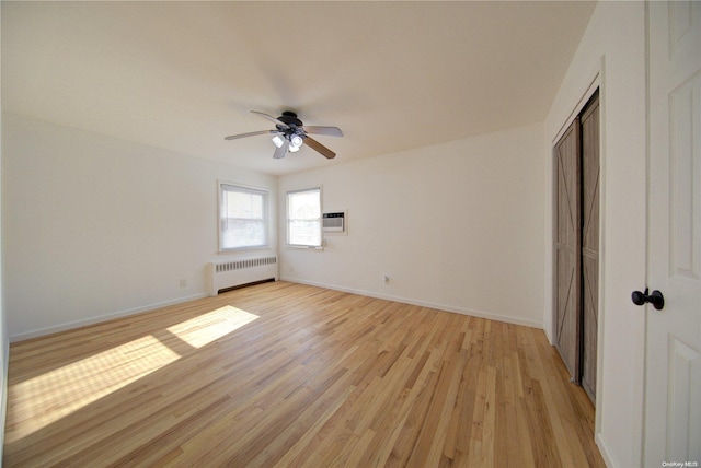 unfurnished bedroom with ceiling fan, light hardwood / wood-style floors, and radiator