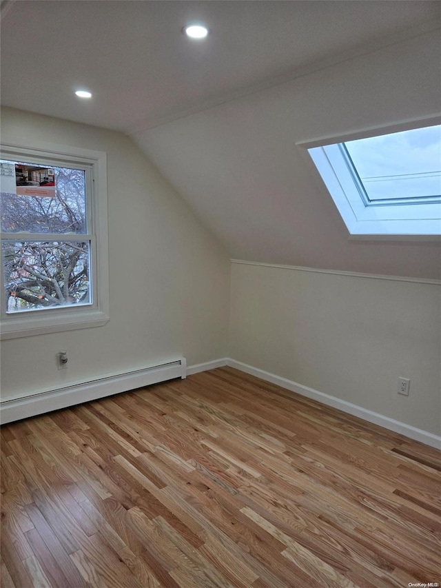 additional living space with light hardwood / wood-style floors, vaulted ceiling, and baseboard heating