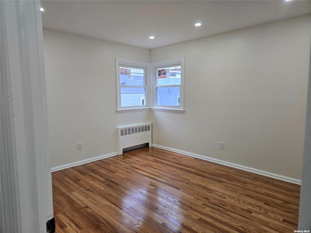 unfurnished room featuring radiator and dark wood-type flooring