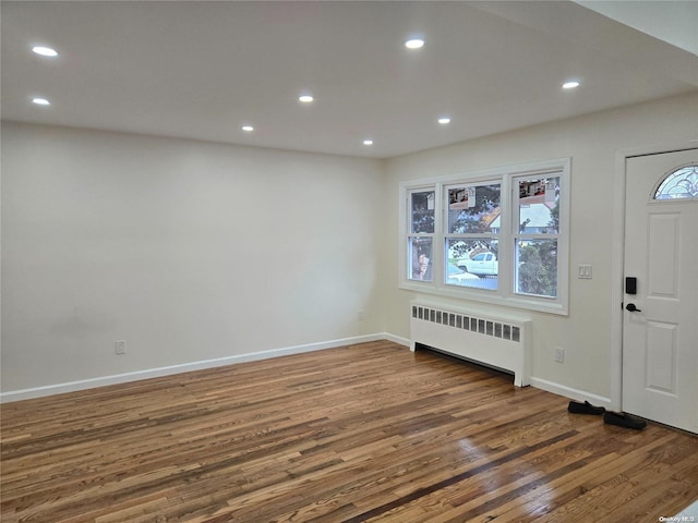 foyer entrance with dark hardwood / wood-style flooring, radiator heating unit, and plenty of natural light