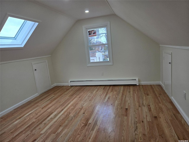 bonus room featuring light hardwood / wood-style floors, lofted ceiling with skylight, and a baseboard radiator