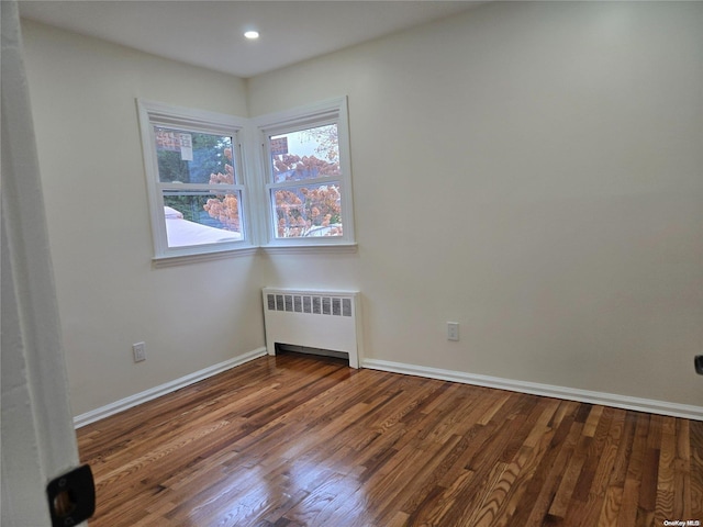 unfurnished room with dark hardwood / wood-style flooring and radiator heating unit