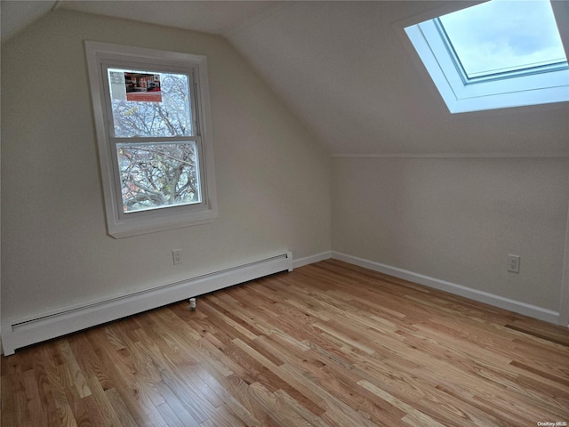 bonus room featuring lofted ceiling with skylight, a baseboard radiator, and light hardwood / wood-style floors