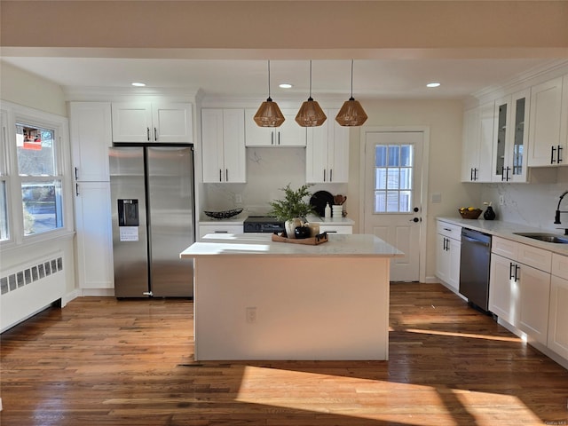 kitchen featuring radiator, stainless steel appliances, dark wood-type flooring, pendant lighting, and white cabinets