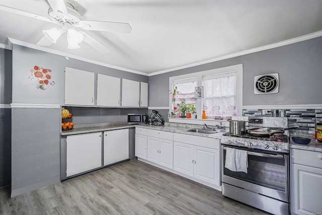 kitchen with appliances with stainless steel finishes, light hardwood / wood-style floors, white cabinetry, and ornamental molding