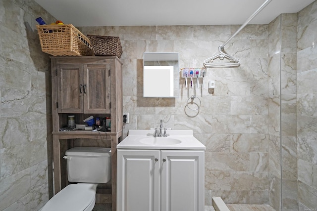 full bathroom with toilet, tiled shower, tile walls, and vanity