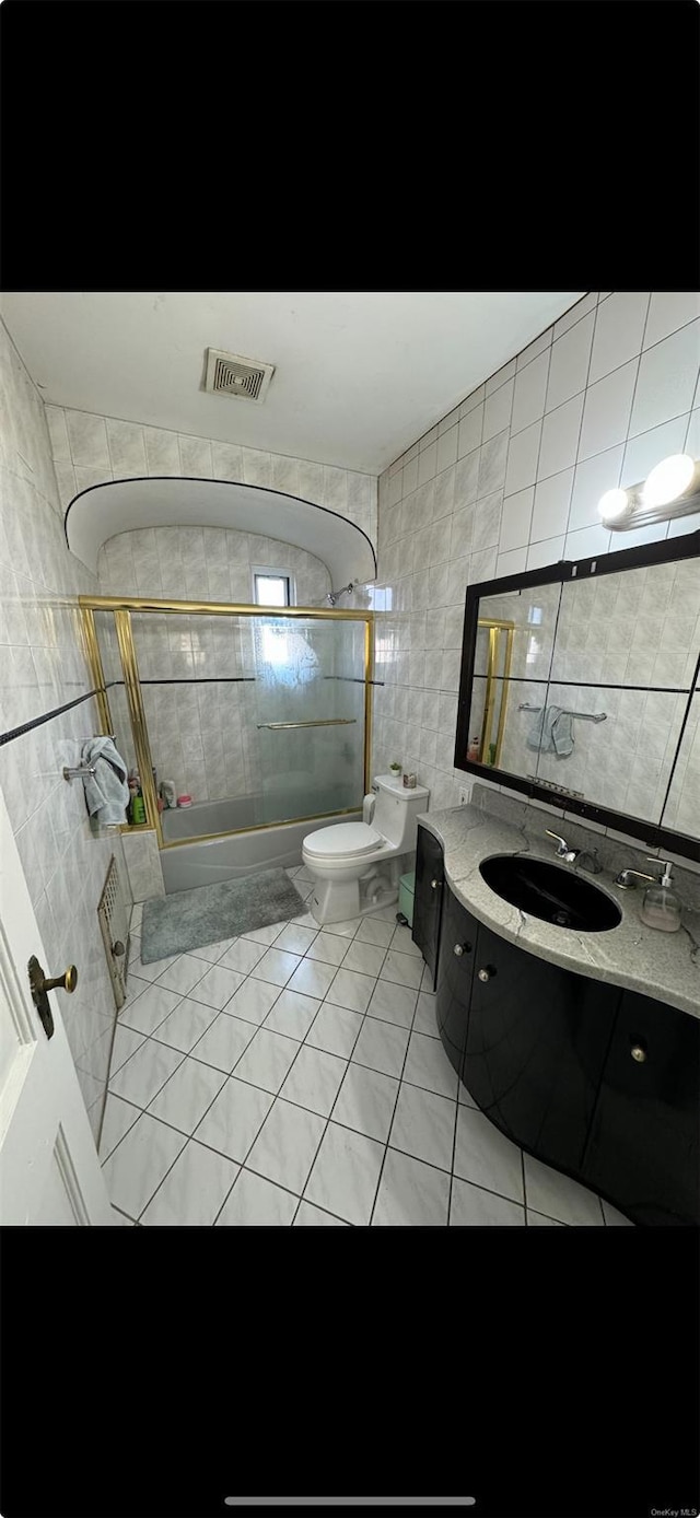 full bathroom with tile patterned flooring, vanity, tile walls, and tiled shower / bath combo