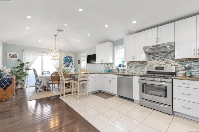 kitchen with appliances with stainless steel finishes, a wealth of natural light, and lofted ceiling