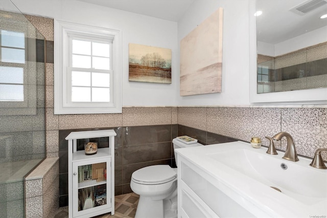 bathroom featuring vanity, toilet, and tile walls