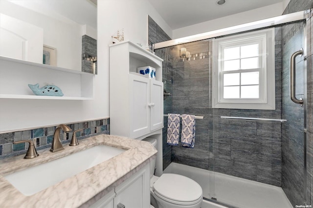 bathroom featuring a shower with door, vanity, and toilet