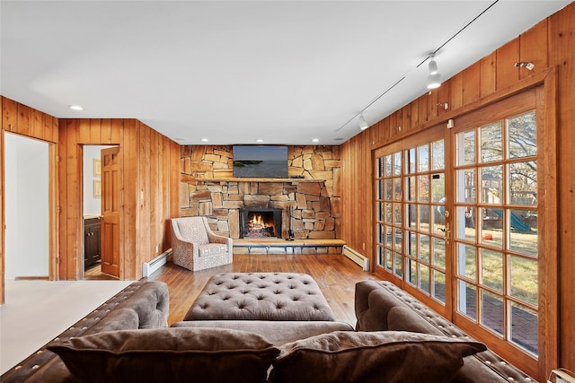 living room featuring a fireplace, light hardwood / wood-style flooring, rail lighting, and a baseboard radiator