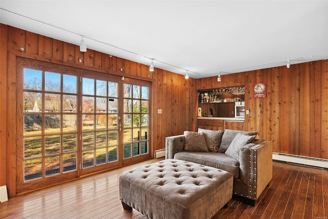 living room featuring wood walls, a baseboard radiator, track lighting, and hardwood / wood-style flooring