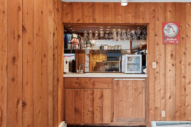 bar with baseboard heating and wooden walls