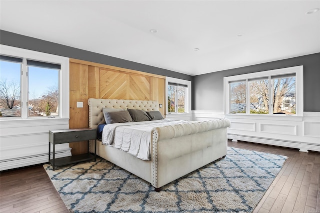 bedroom featuring multiple windows, dark hardwood / wood-style flooring, and a baseboard radiator