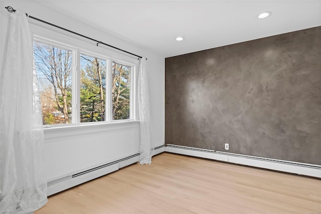 empty room featuring baseboard heating and light hardwood / wood-style floors