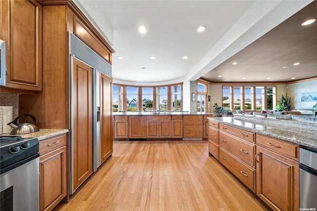 kitchen featuring crown molding, light stone countertops, appliances with stainless steel finishes, light hardwood / wood-style floors, and kitchen peninsula