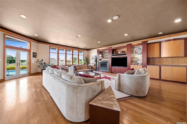 living room with light hardwood / wood-style flooring, a healthy amount of sunlight, french doors, and ornamental molding