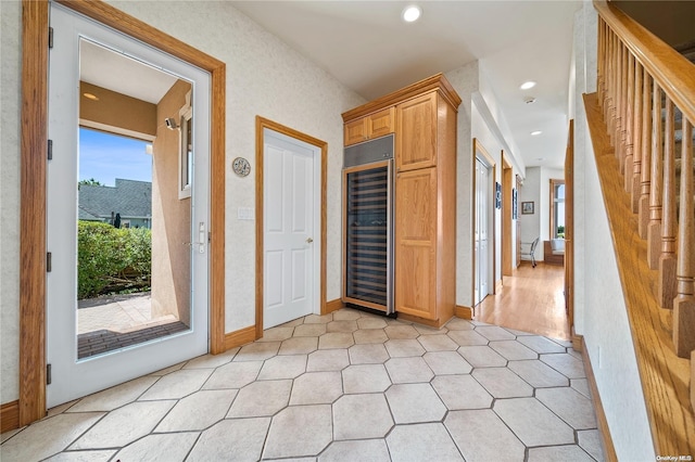 corridor with a healthy amount of sunlight, beverage cooler, and light hardwood / wood-style flooring