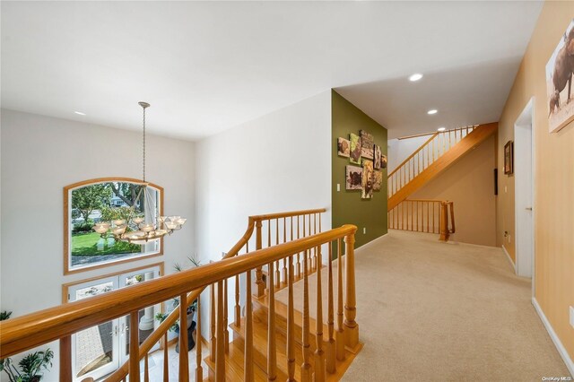 hall featuring light colored carpet and a notable chandelier