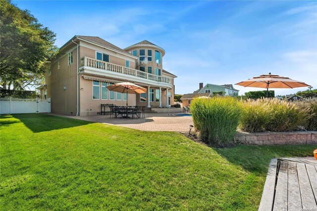 rear view of house with a balcony, a yard, and a patio