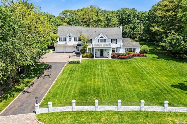 view of front of home featuring a balcony, a front lawn, and a garage