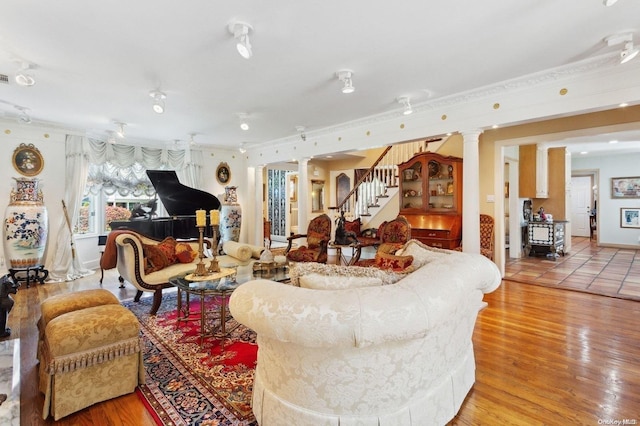 living room featuring decorative columns, ornamental molding, and light wood-type flooring