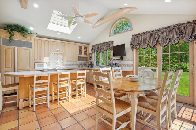 kitchen featuring decorative backsplash, a skylight, ceiling fan, light tile patterned floors, and high vaulted ceiling