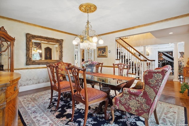 dining space featuring hardwood / wood-style floors, decorative columns, an inviting chandelier, and ornamental molding