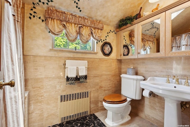 bathroom featuring tile patterned floors, toilet, radiator, and tile walls