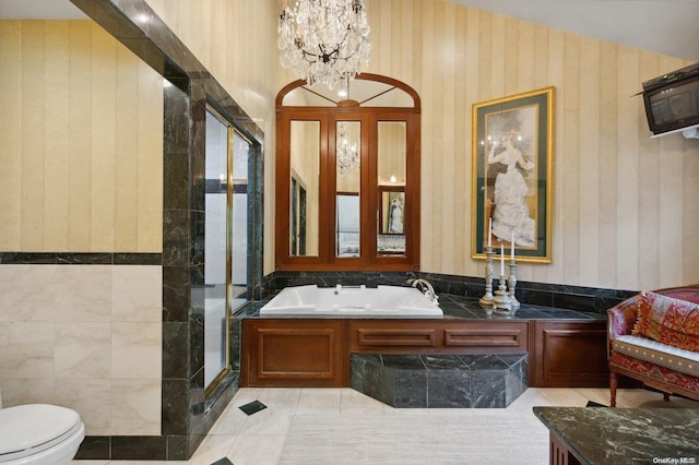 bathroom with tile patterned flooring, a chandelier, toilet, independent shower and bath, and tile walls