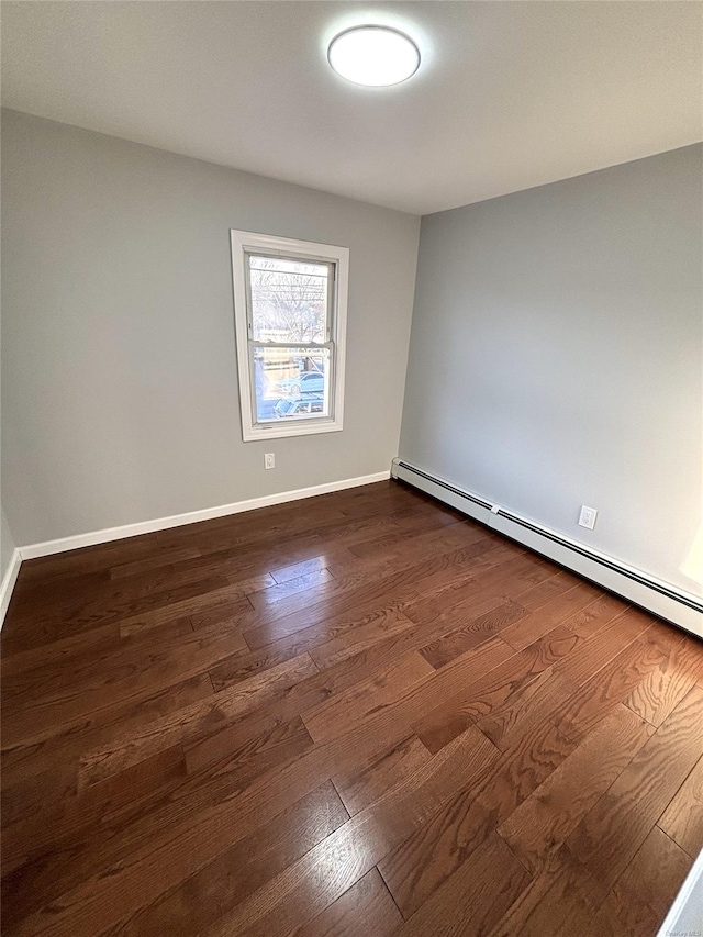 empty room featuring dark hardwood / wood-style floors and a baseboard heating unit