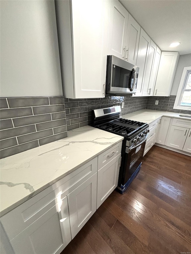 kitchen with light stone counters, range with gas cooktop, decorative backsplash, dark hardwood / wood-style flooring, and white cabinetry