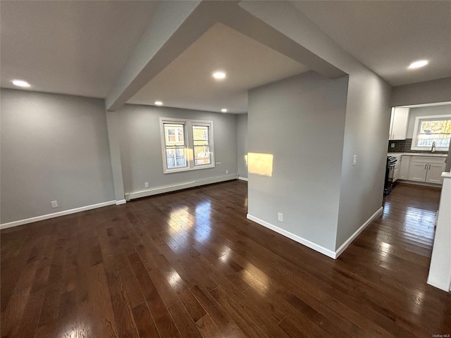 unfurnished room with sink, baseboard heating, and dark hardwood / wood-style flooring