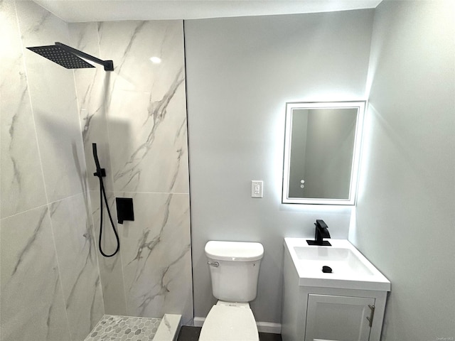 bathroom with toilet, vanity, and tiled shower