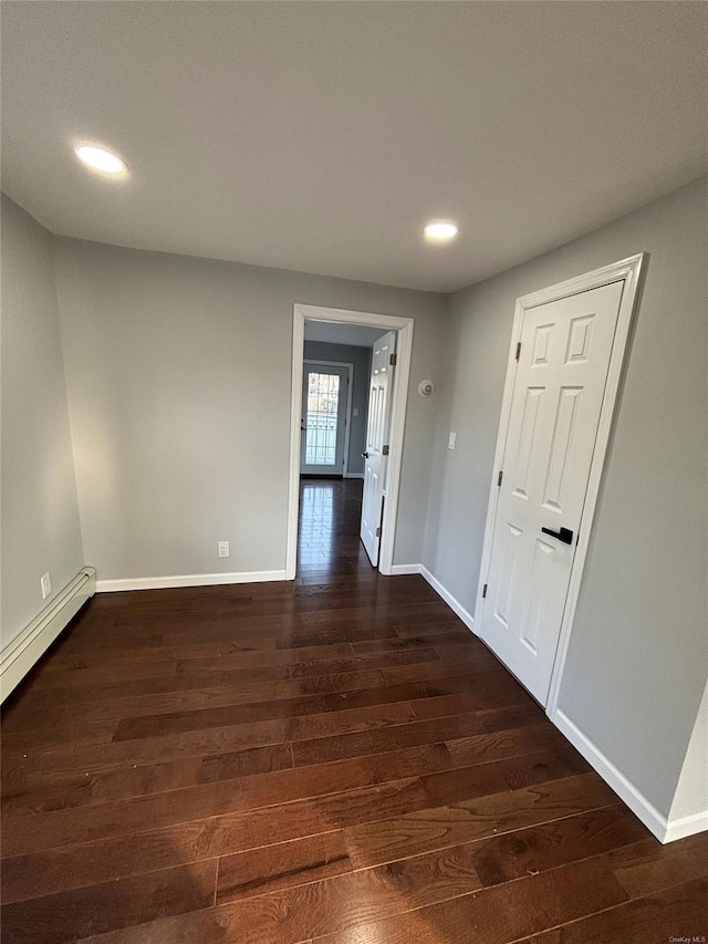 empty room featuring a baseboard radiator and dark hardwood / wood-style floors