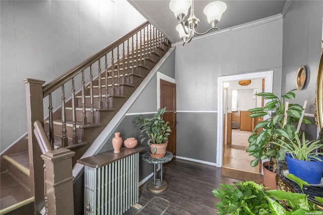 staircase featuring crown molding, a notable chandelier, and hardwood / wood-style flooring