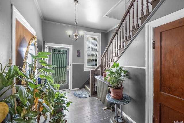 foyer with hardwood / wood-style floors, an inviting chandelier, and ornamental molding