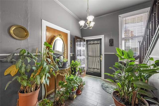 entryway featuring crown molding, hardwood / wood-style floors, and a chandelier